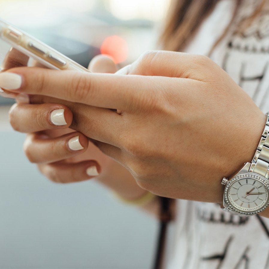 Photo by Paul Hanaoka woman holding iPhone during daytime